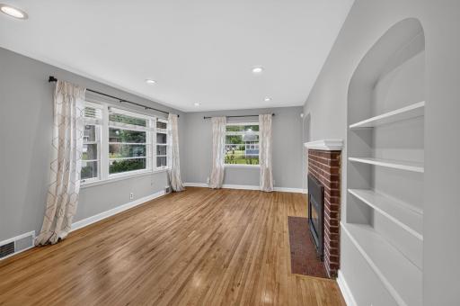 Light-filled living room features hardwood floors, fireplace and charming built-ins.