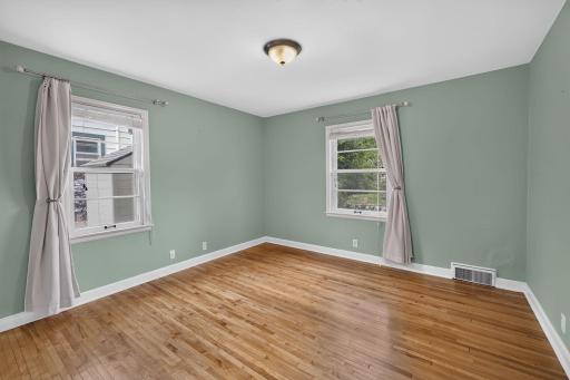 Main-level bedroom features hardwood floors and windows on two sides.