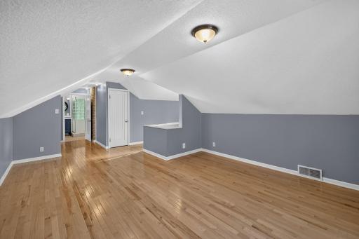Spacious upper-level primary suite features hardwood floors and charming angled ceilings.