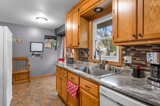 Warm wood cabinetry, a tile backsplash, and generous counter space complement a window above the sink overlooking the backyard