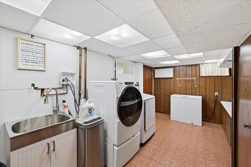 Bright and inviting, the finished laundry room combines practicality and convenience with a newer utility sink and Samsung washer and dryer added in 2023-2024. Mechanicals are in a closet at the other end of the room.