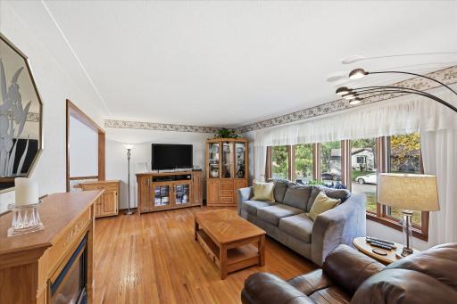 The inviting living room features beautiful hardwood floors and a stunning Marvin bow window that fills the space with natural light.