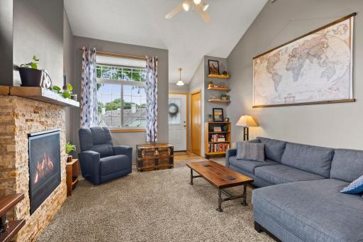 A welcoming entry area with a convenient coat and shoe closet. Opens into the spacious living room, featuring a vaulted ceiling and cozy fireplace.