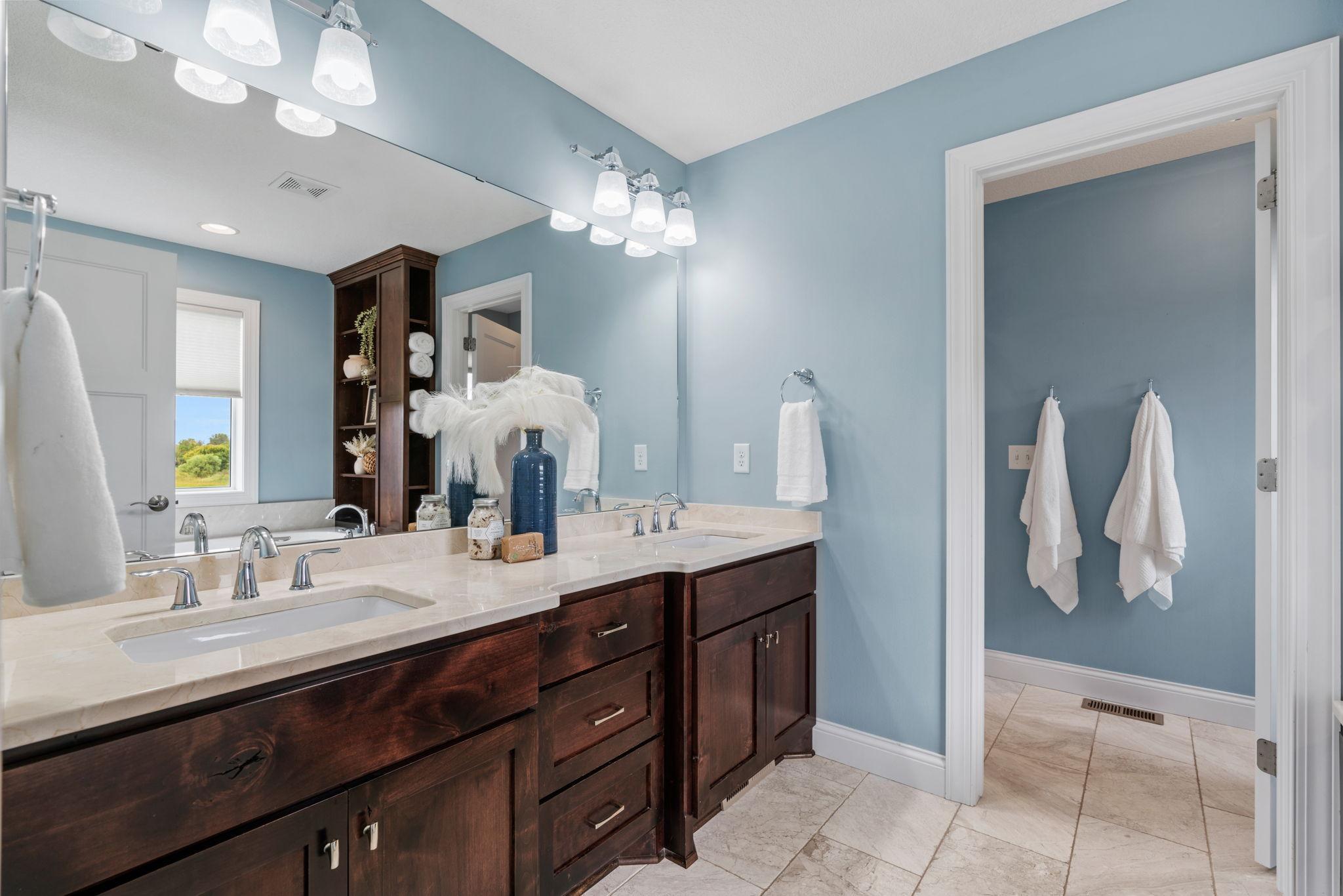 Vaulted Primary Suite w/ ensuite bath featuring dual sinks, separate tub/shower + WIC.