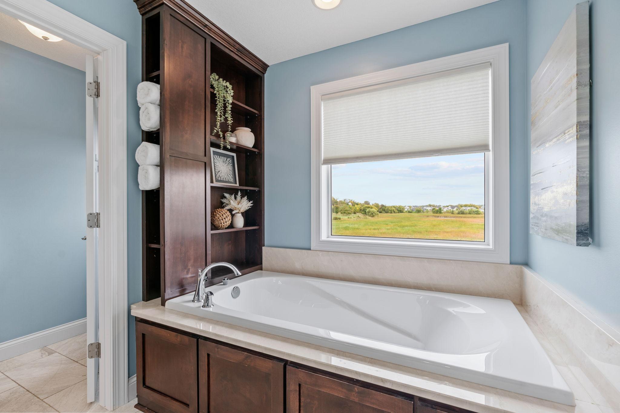 Vaulted Primary Suite w/ ensuite bath featuring dual sinks, separate tub/shower + WIC.