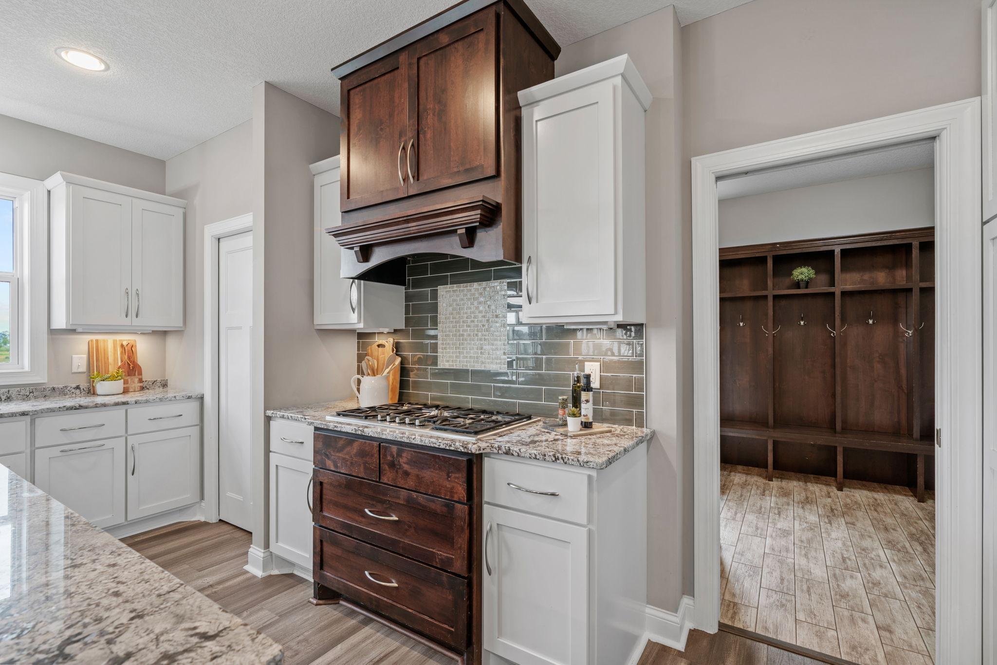 Gourmet Kitchen w/ granite + butcher-block counters, white cabinetry, subway tile backsplash, SS apps incl Thermador gas cooktop + double ovens, hood, beverage fridge + pantry