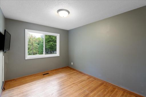 One of three main-level bedrooms featuring beautiful floors and a large window for natural light.