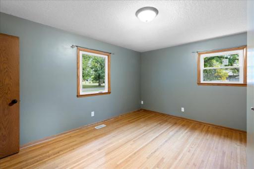 Spacious main-level primary bedroom features hardwood floors and windows on two sides for plenty of natural light.