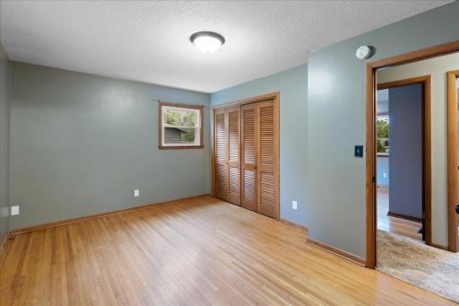 Another view of the spacious main-level primary bedroom, complete with hardwood floors and a generous closet space.