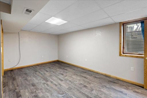 Another view of the spacious lower-level bedroom, complete with durable flooring and an egress window for natural light.