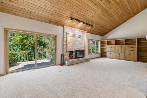 Living room with deck and large windows overlooking green spaces...