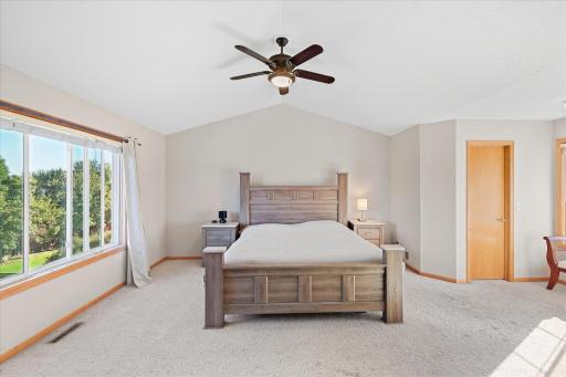 Spacious primary suite designed as a private retreat with a vaulted ceiling and 2 walk in closets.