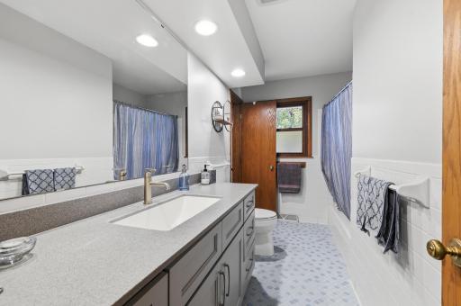 Main level full bathroom with original blue tile and updated vanity with an abundance of storage!