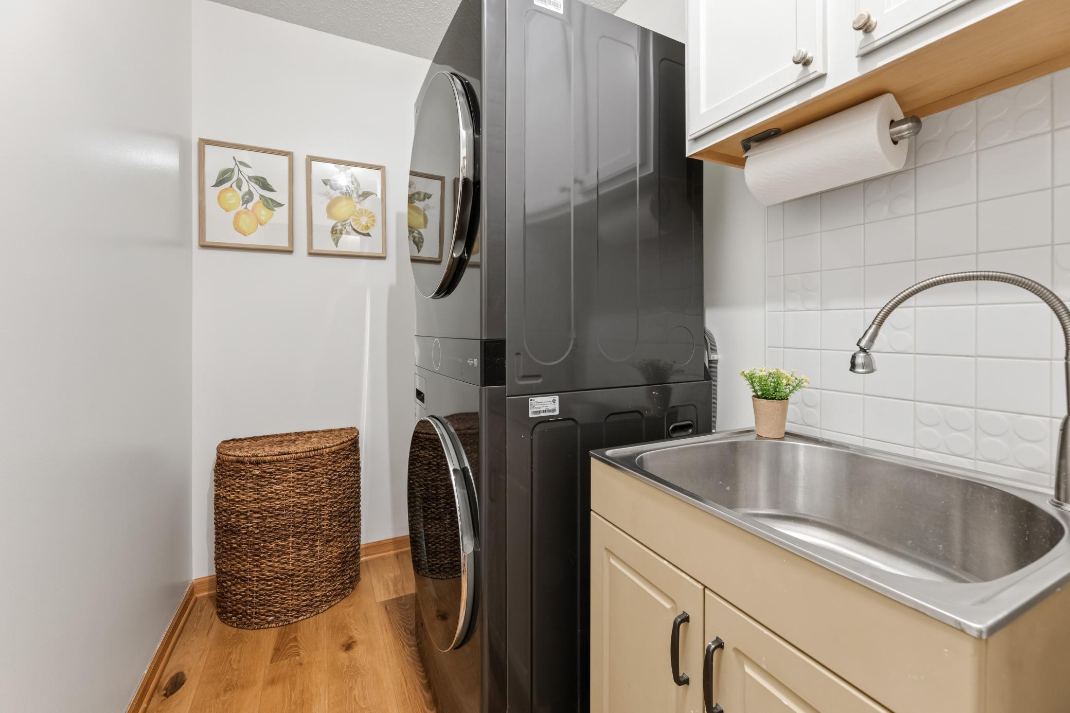 Main-level laundry with utility sink and storage.