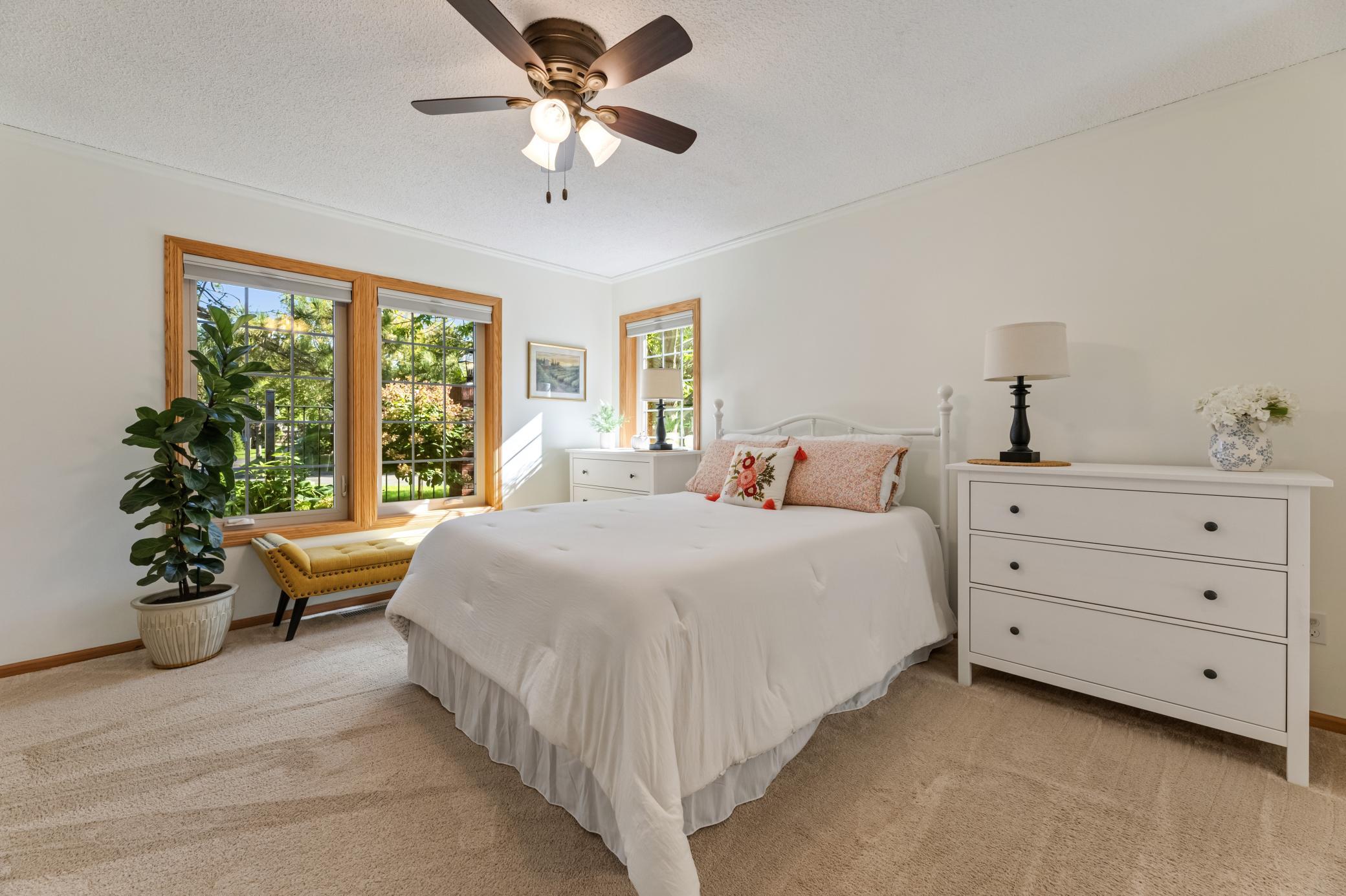 This space offers plush carpeting, neutral tones, and a ceiling fan for added comfort.