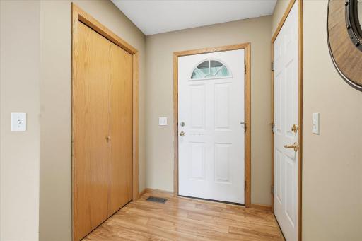 Welcoming front foyer features LVP flooring, natural wood trim, a convenient coat closet, and direct access to the finished three-car garage.
