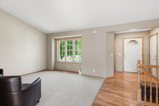 Another view of the bright living room and welcoming foyer, highlighting the open layout and natural woodwork throughout.