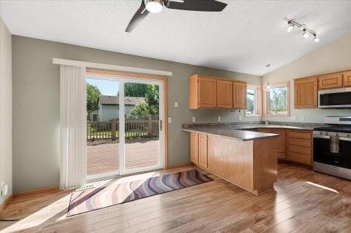 Bright kitchen and dining area features LVP flooring, granite countertops, stainless steel appliances, and direct access to the 18x16 maintenance-free deck.