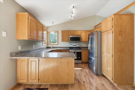 Spacious kitchen offers granite countertops, plentiful cabinetry, LVP flooring, stainless steel appliances, and a gas range.