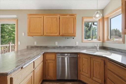 Kitchen workspace features granite countertops, an undermount sink, stainless steel dishwasher, abundant cabinetry, and windows providing plenty of natural light.