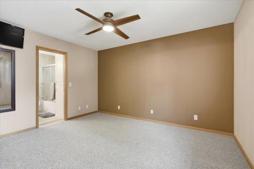 Primary bedroom features newer carpet, ceiling fan, and convenient direct access to the updated full bathroom.