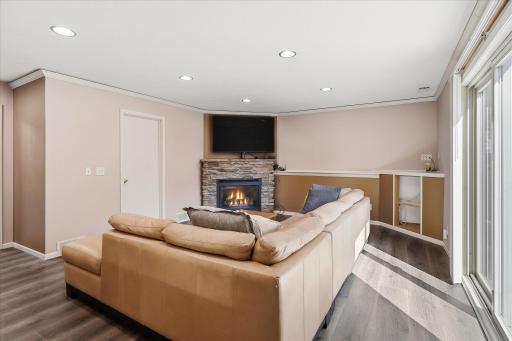 Cozy gas fireplace with stone surround provides an inviting focal point in the spacious lower-level family room.