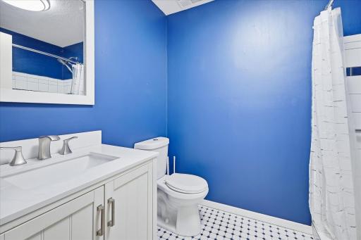 Convenient lower-level bathroom features a white vanity with modern fixtures, tile flooring, and a walk-in shower.