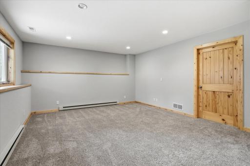 Expansive finished lower-level room features beautiful knotty pine trim and a knotty pine door, adding warmth and character to this versatile living space.
