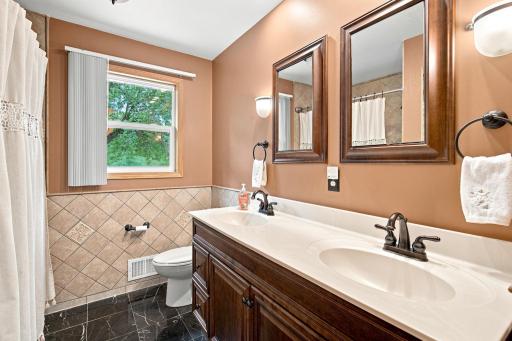 Main floor full bath features heated floors, tile flooring and tiled walls.