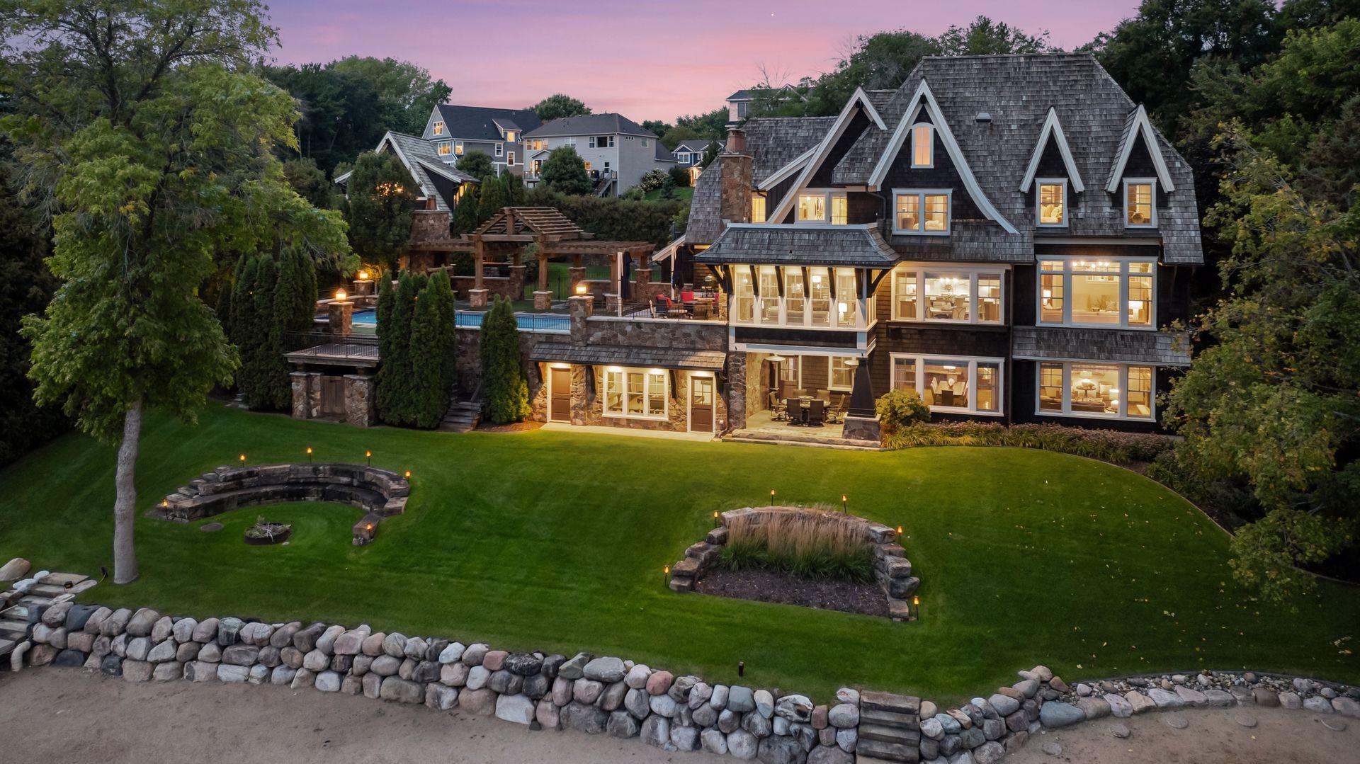 Rear exterior with expansive lawn and lakeside firepit
