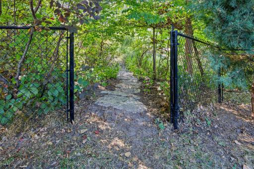 Yard leads to a path with bridge to pond, pool, and tennis courts