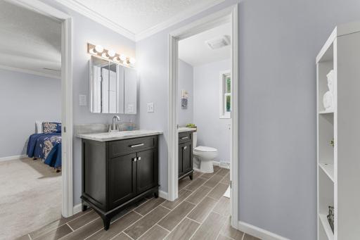 The bathroom features tile flooring, two single quartz vanities, and a tub and shower combination.