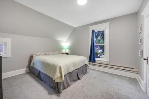 Upstairs, the first spacious bedroom features plush carpet and neutral tones.