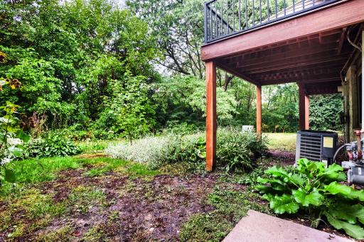 Rear exterior with maintenance-free deck, lower-level walkout, and wooded backdrop.