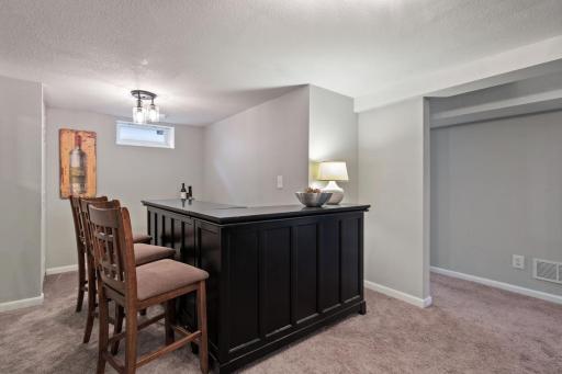 Entertain in style with this inviting lower-level bar area! The beautiful built-in bar stays with the home, creating the perfect spot for hosting friends, game nights, and relaxing gatherings.