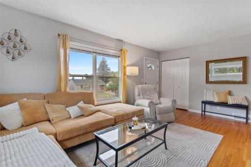 Light and bright south-facing living room featuring large windows, beautiful hardwood floors, and fresh, updated paint. A spacious entry closet adds convenient storage while welcoming you into this inviting space.