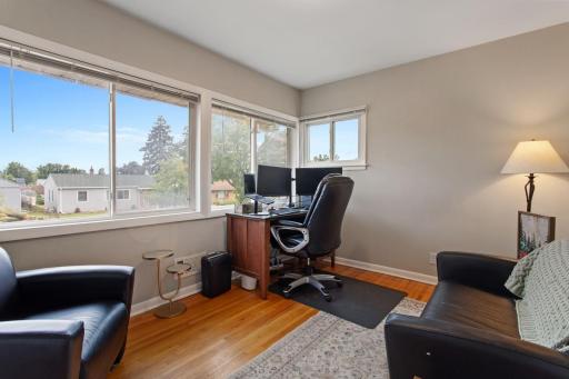 Light and bright south-facing bedroom with nearly a wall of windows plus a side window, filling the space with natural light. Neutral paint makes this versatile room perfect for a bedroom or home office. The hall also has a large storage closet.