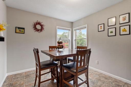 Bright, spacious informal dining area with room for a large table, neutral paint, two windows overlooking the backyard and side yard, and easy-care flooring. A welcoming space for everyday meals and entertaining.