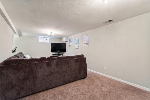 Cozy finished lower-level family room with fresh paint and new light fixtures. A versatile nook adds extra space for a home gym, reading area, or quiet retreat.