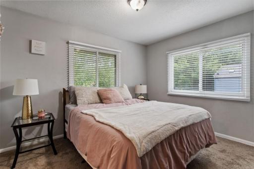 Inviting primary bedroom with backyard views, fresh neutral paint, a large closet, and an attached bonus roomâperfect for an office or nursery. White six-panel doors, trim, and blinds complete the look.