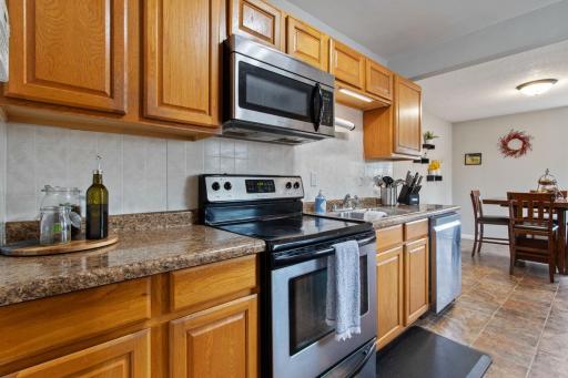 Bright galley-style kitchen with beautiful cabinetry, ample cabinet and counter space, and stainless steel appliances. Side door provides access to the fully fenced backyard and concrete patioâperfect for summer entertaining. There's also a pantry!
