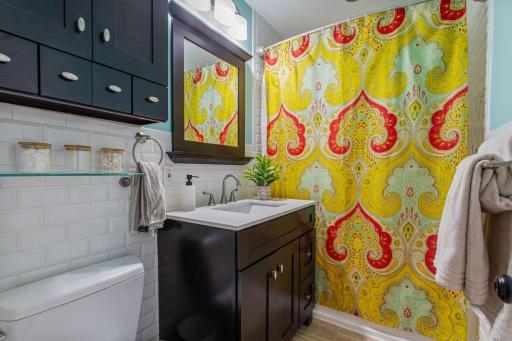 Updated main-floor full bath with ceramic tile floors, tub surround and half walls, plus a modern vanity with matching medicine cabinet. Centrally located for everyday convenience. The hallways have gleaming hardwood floors & a handy laundry chute!