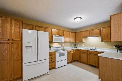 The well-maintained kitchen features warm wood cabinetry, white appliances, and plenty of workspace.