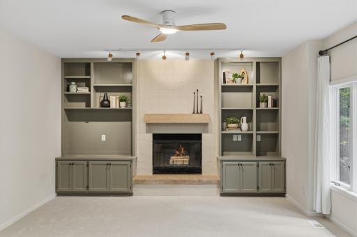 Family Room offers a wood burning fireplace that features a white oak mantel, porcelain tile surround and hearth. Built-in enameled cabinets frame the fireplace and offers storage open display shelving and large opening for a TV