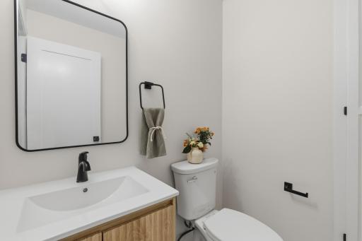 1/2 bathroom features natural wood vanity cabinet with fluted doors, linen closet and ceramic tile flooring