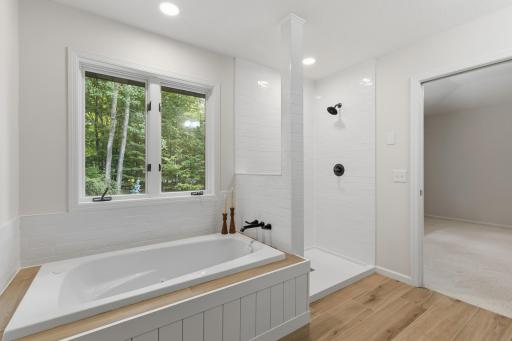New jetted tub situated on a tile deck and surround w/ wall mounted faucet. The shower features a subway tile surround, with rain glass enclosure