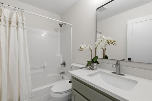Full bathroom features enameled vanity cabinet with quartz top, ceramic tile flooring and a linen closet located in the hall