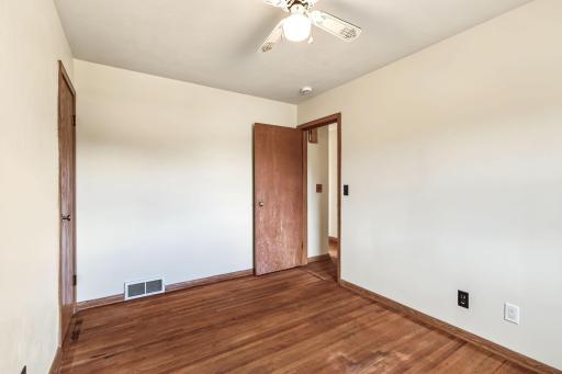 Main-level bedroom featuring hardwood floors, neutral walls, wood trim, and flexible furniture placement.