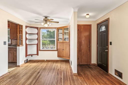 Bright dining area with hardwood floors, wood cabinetry, built-in shelving, and direct access to the kitchen.