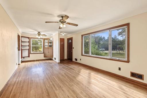Open living and dining area with hardwood floors, large windows, ceiling fans, and an easy-flowing main-level layout.